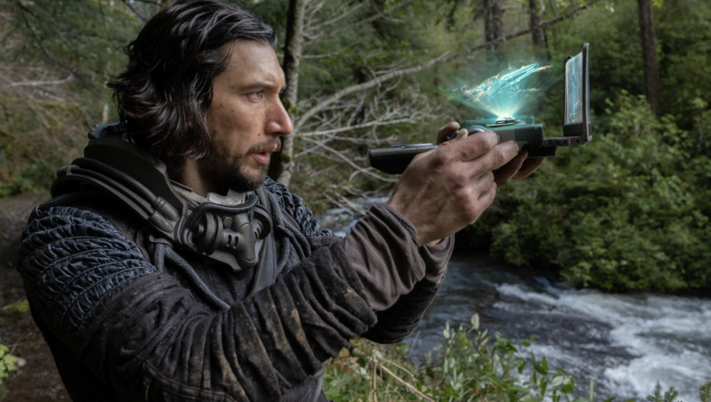 Adam Driver in 65 (2023). Survivor with futuristic device in wilderness. Sci-fi movie scene.