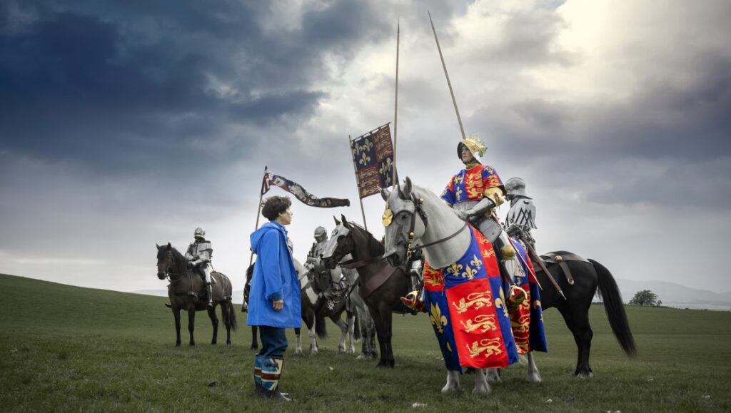 The Lost King — Stephen Frears The Lost King movie scene: Sally Hawkins with knights on horseback in a field.