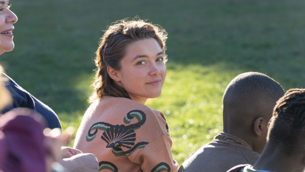 Florence Pugh in A Good Person, directed by Zach Braff. Pugh smiles, sitting outside.