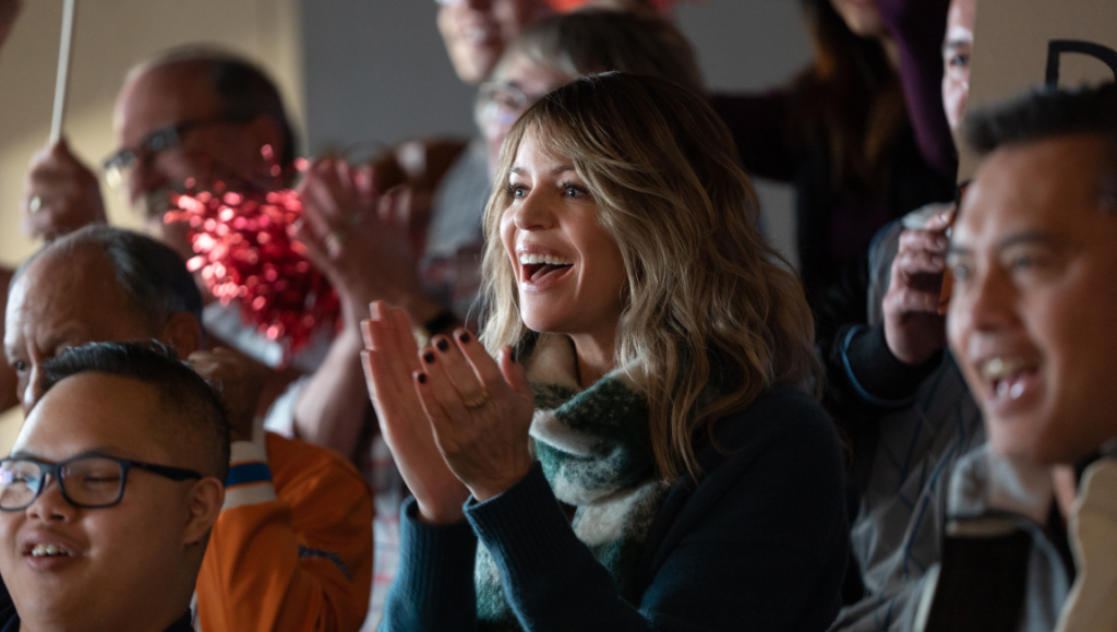 Shauna Townley in Champions movie. Crowd cheering and clapping. Focus Features film.