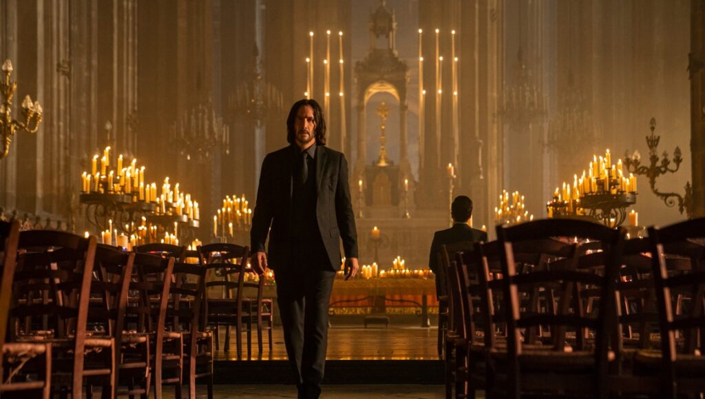 Keanu Reeves as John Wick in John Wick: Chapter 4 walking in a candlelit church.