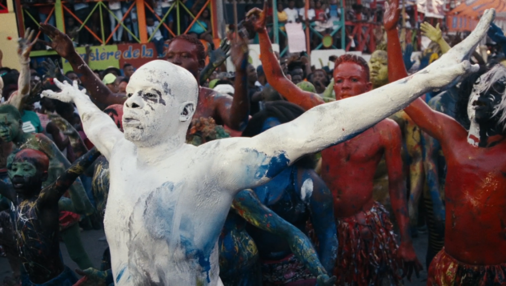 Kite Zo A: Leave the Bones SXSW film review image. Performers painted in vibrant colors dance in a lively Haitian festival scene.