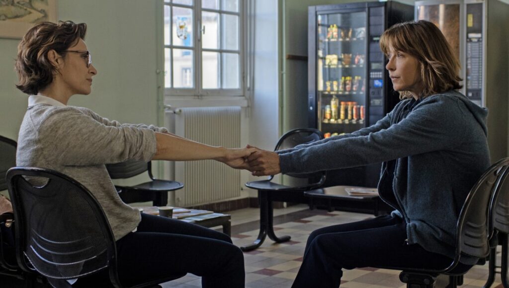 Everything Went Fine movie still. Two women holding hands, seated in a waiting room. French film.