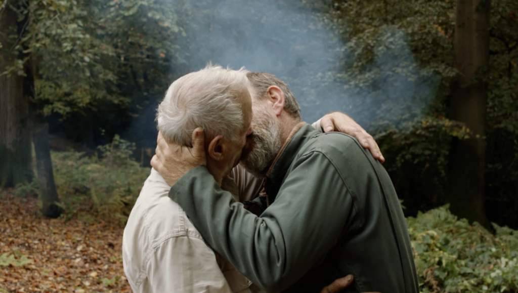 A Prince film still: Two men embrace outdoors. Pierre Creton's movie explores themes of love and nature.