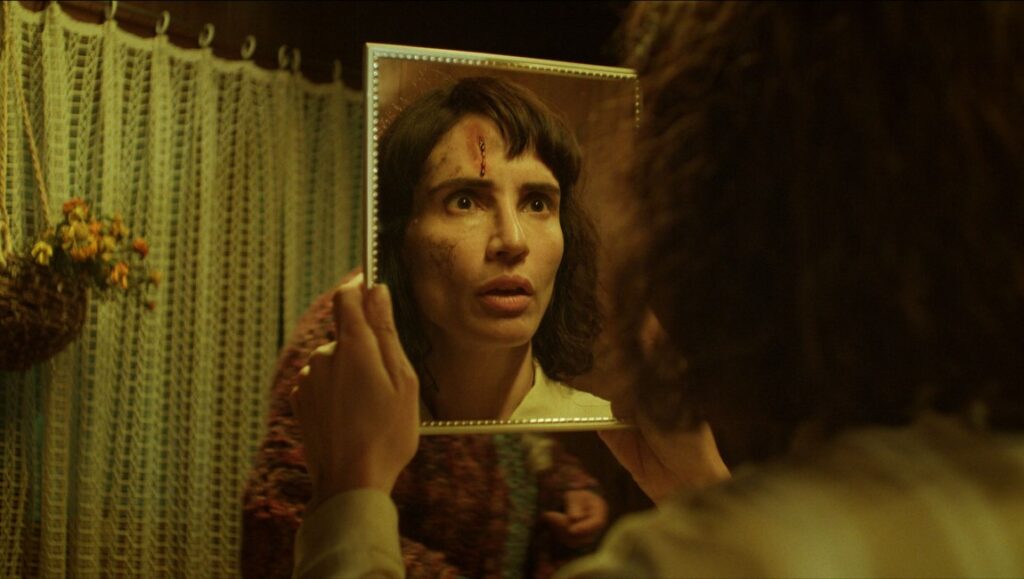 The Cow Who Sang a Song Into the Future movie still. Woman with a head wound looks in a mirror. Francisca Alegría film.