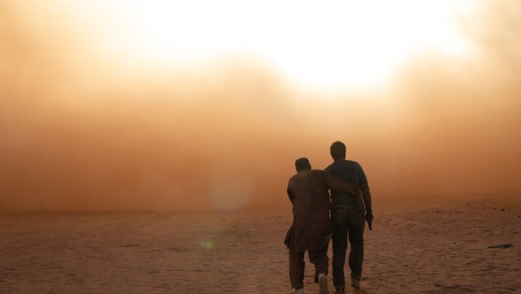 Kandahar — Ric Roman Waugh Kandahar movie image: Two men walk through a dusty, orange desert landscape.