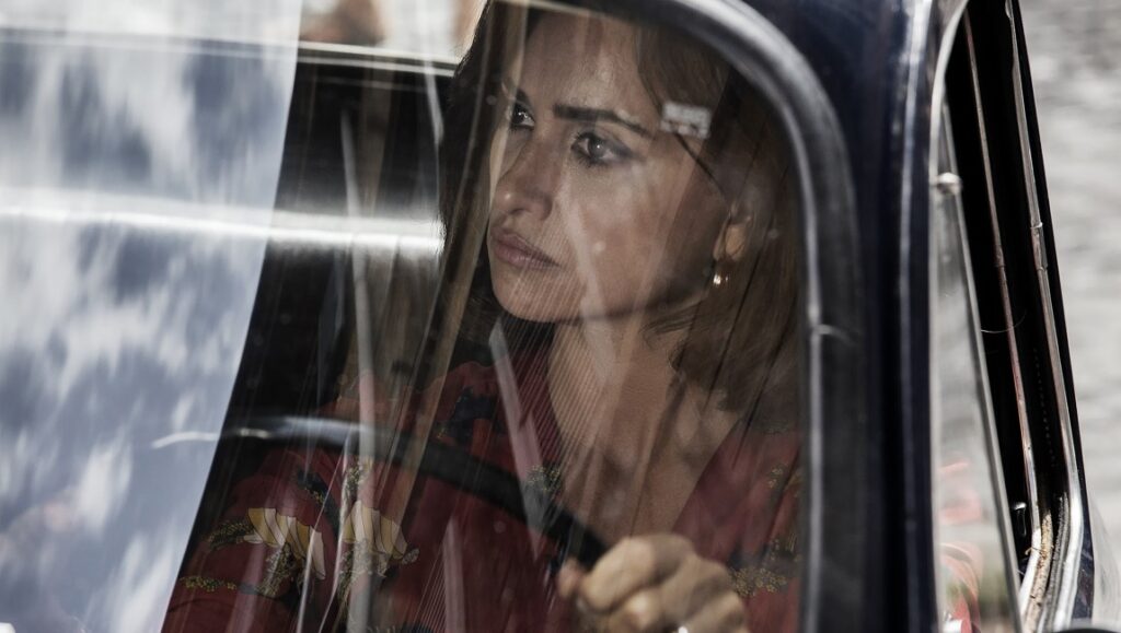 Penélope Cruz in L'immensità. Actress driving a car, floral dress. Movie still.