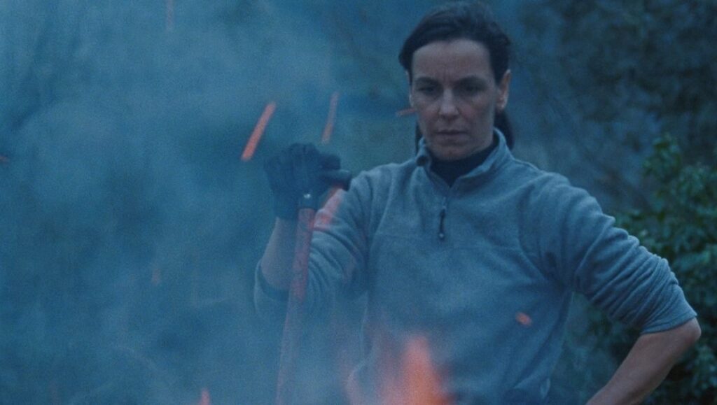 Legua film review: Woman tending fire. Still from João Miller Guerra and Filipa Reis' Cannes '23 film.