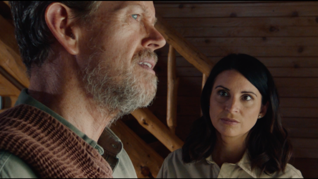 Outpost movie scene featuring Joe Lo Truglio and a woman in a serious conversation.