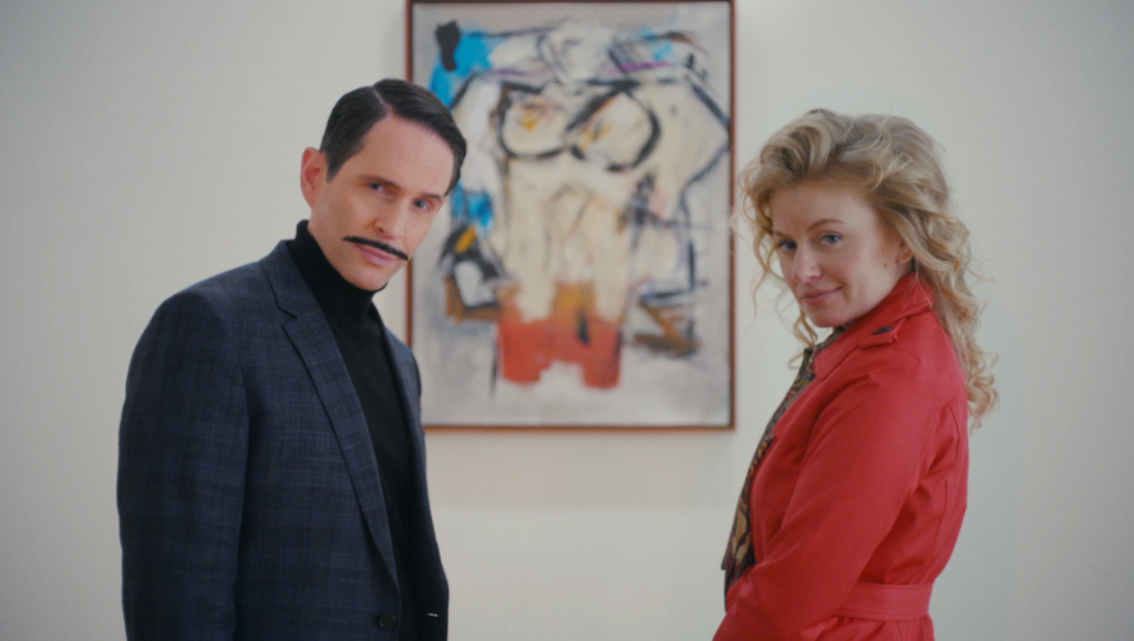 The Thief Collector film still. A man and woman stand before an abstract painting.