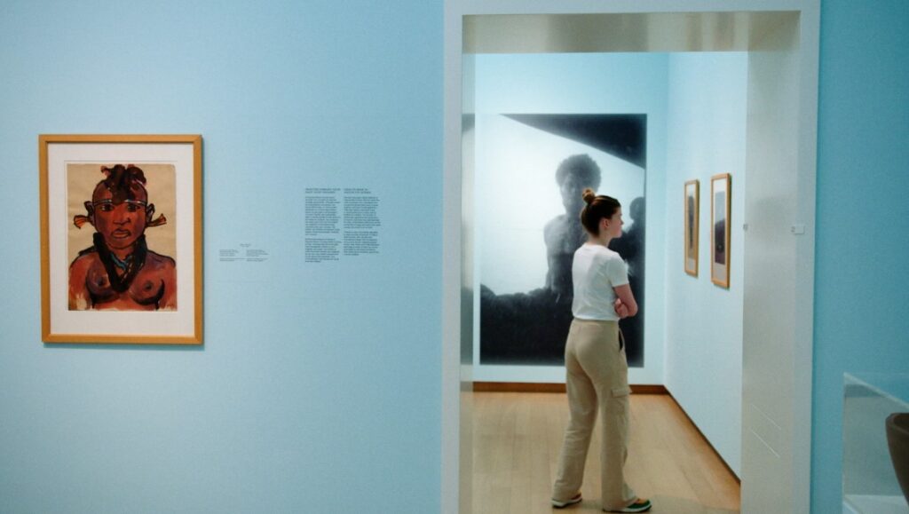 White Balls on Walls — Sarah Vos Art gallery view: Woman viewing Sarah Vos' White Balls on Walls exhibit, Icarus Films. Artwork on display.