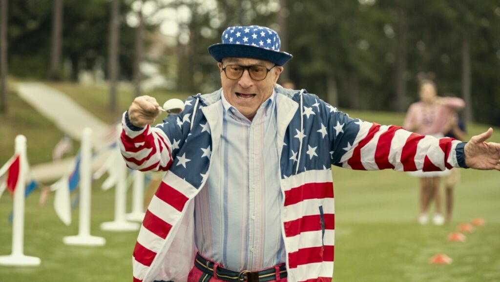 About My Father movie still: Robert De Niro in American flag jacket on golf course.