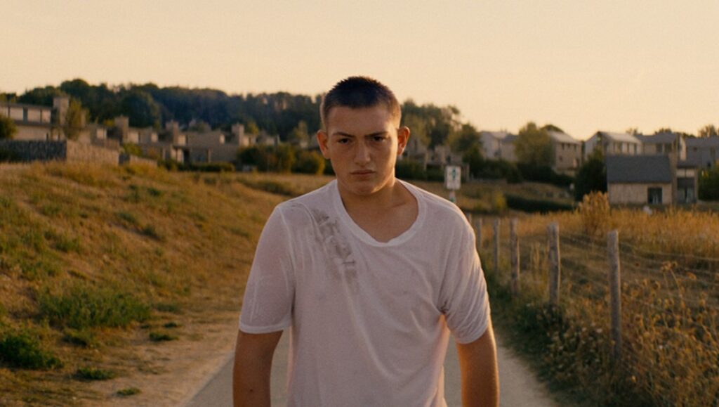 It's Raining in the House film still. Teen boy in wet t-shirt walks on path. Cannes '23 review.