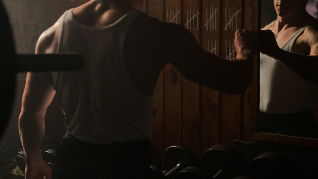 Arnold — Lesley Chilcott Arnold Schwarzenegger in Arnold Netflix documentary. Bodybuilder flexing in gym with tally marks.