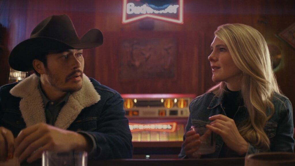 Downtown Owl movie scene: Man in cowboy hat and woman at bar with Budweiser sign.