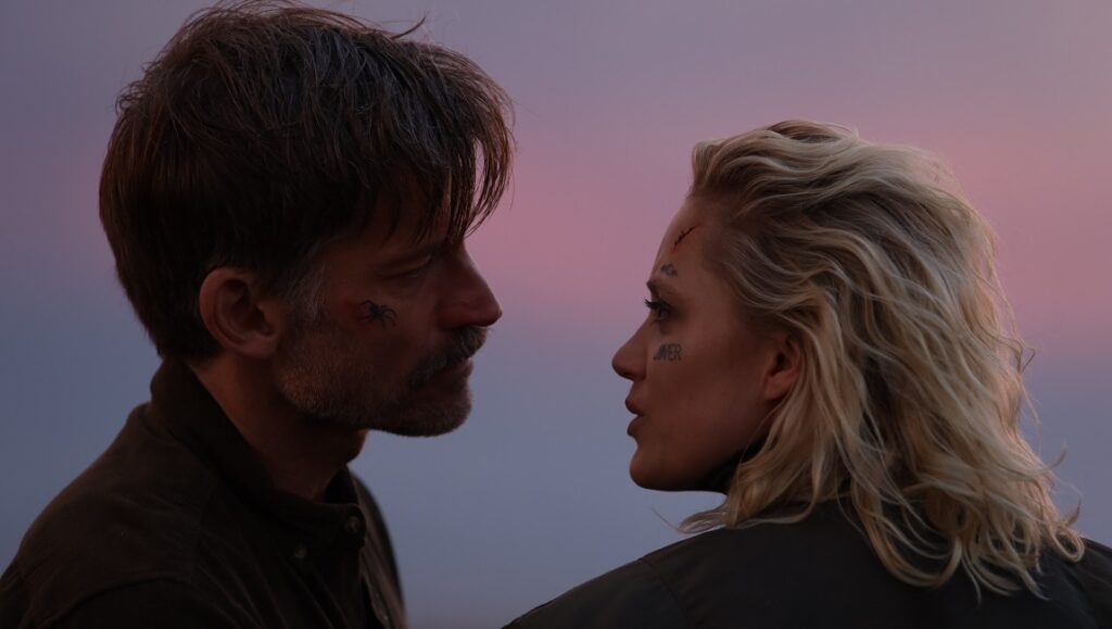 Nikolaj Coster-Waldau and Clara Rugaard in Against the Ice look at each other. Drama, survival, historical adventure.