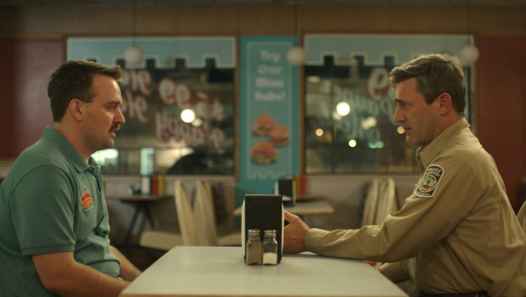Jon Hamm and Will Forte in Maggie Moore(s) at a diner table. Movie scene.