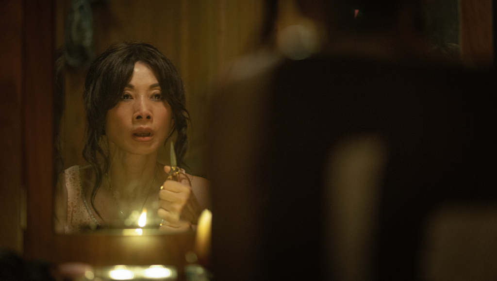 Back Home film still at NY Asian Film Festival: Woman with scissors reflected in mirror, candlelit.