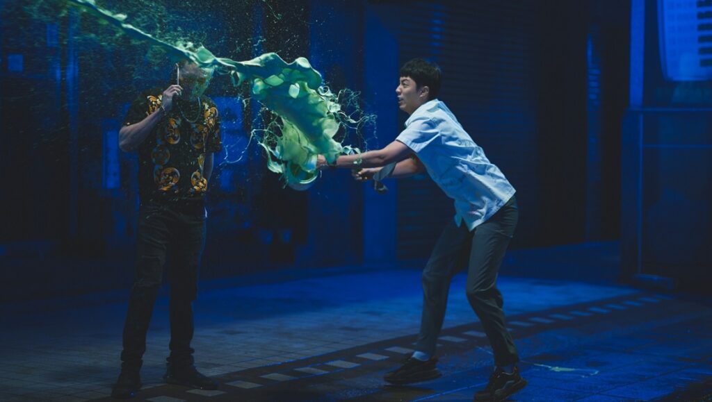 Bad Education film still from New York Asian Film Festival 2023. Two men, green liquid explosion.