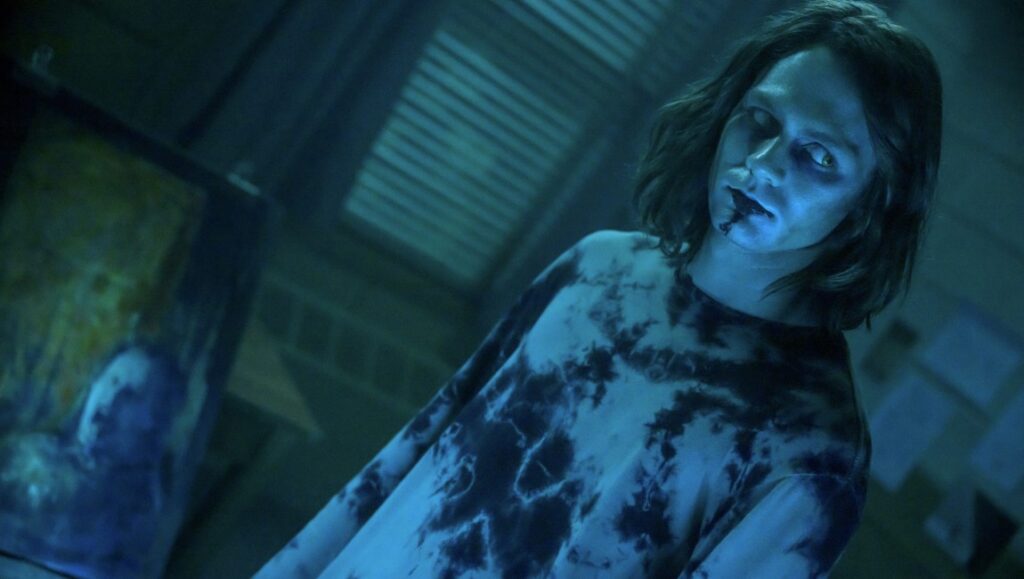 Insidious: The Red Door — Patrick Wilson Insidious: The Red Door scene. A ghostly figure with dark eyes and blood on their face. Horror movie image.