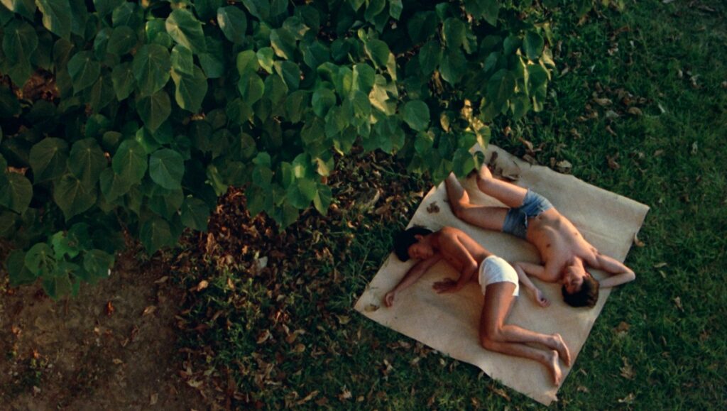 Still from Nomad at New York Asian Film Festival 2023. Two people lie on a blanket in nature.