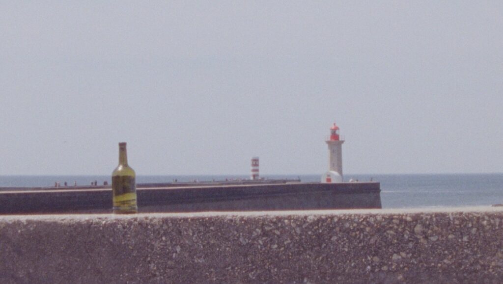 Seascape view with a bottle on a wall, pier, and lighthouse. Coastal scene.