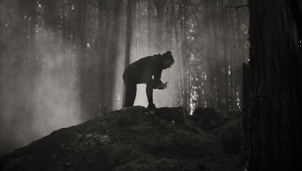 Monochrome still from Quicksand film. Person trapped in quicksand in a dense, foggy forest. Andrés Beltrán film.