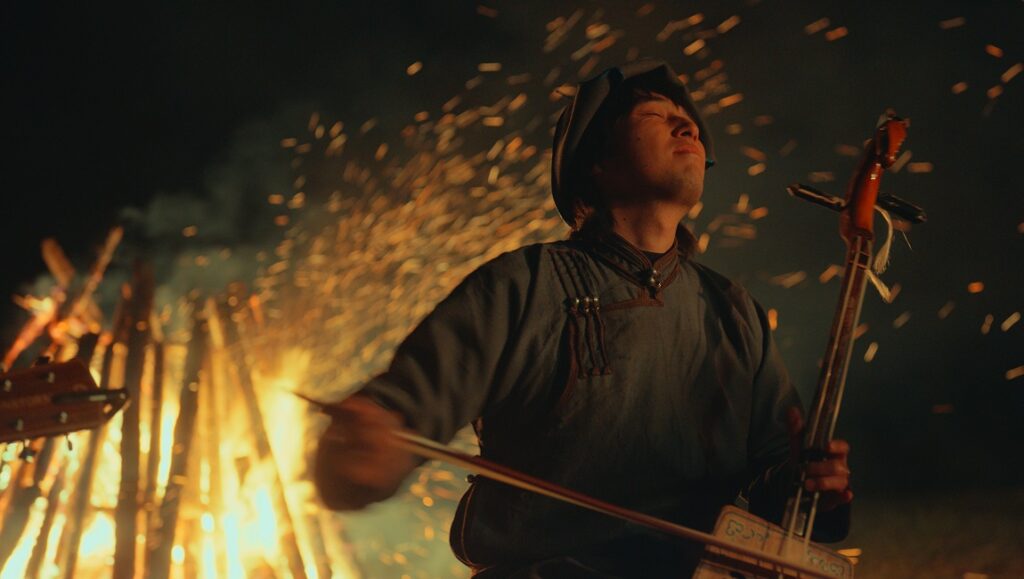 The Cord of Life film still from New York Asian Film Festival 2023. Mongolian musician playing Morin Khuur by fire.