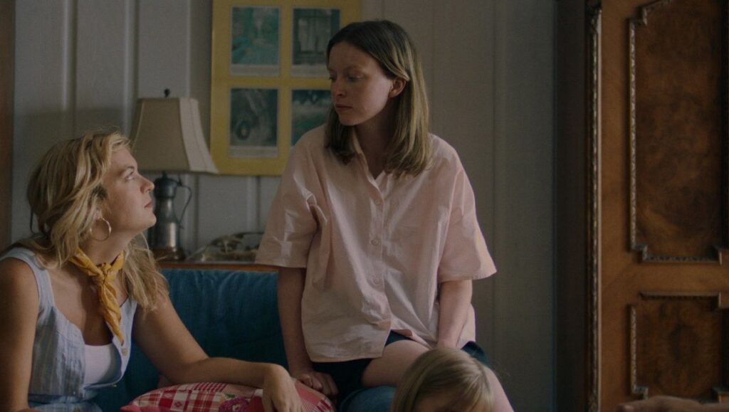 Family Portrait film still from Locarno Film Festival. Two women sit on a couch, one looks up at the other.