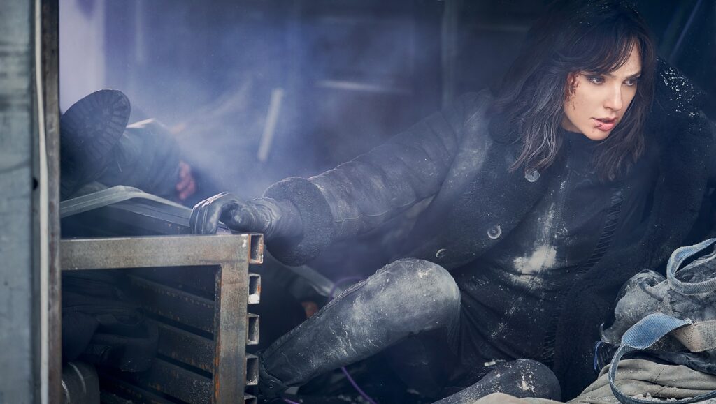 Heart of Stone — Tom Harper Gal Gadot in Heart of Stone. Action scene with dust and damage. Tom Harper film.