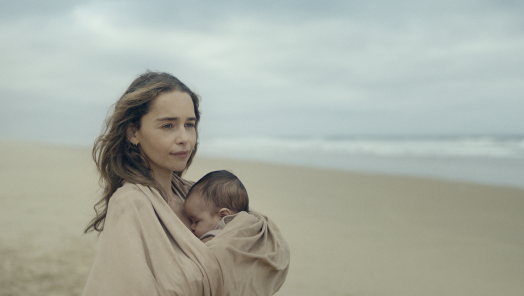 The Pod Generation — Sophie Barthes The Pod Generation movie still: Sophie Barthes directs Emilia Clarke holding a baby on a beach.