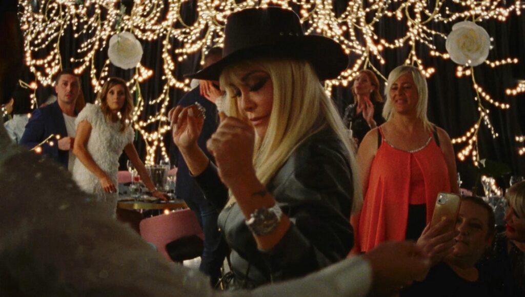 Vera, by Tizza Covi & Rainer Frimmel. Woman in hat at event. Film still from drama movie.