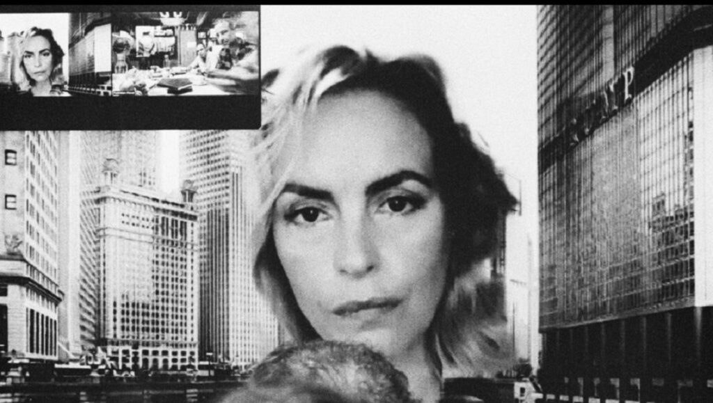 Black and white film still from Do Not Expect Too Much, Locarno Film Festival 2023. Woman's face with city buildings.