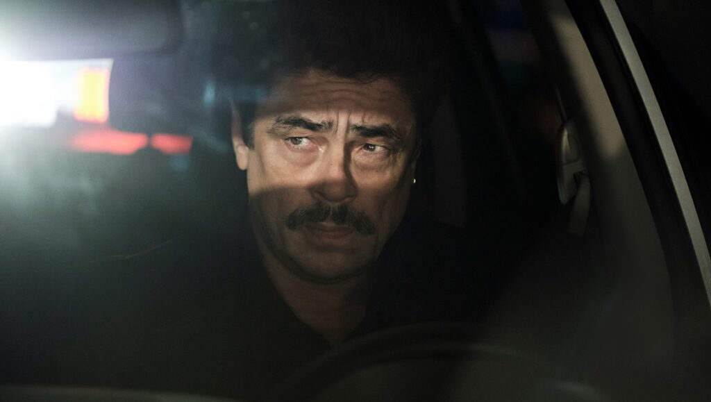 Benicio Del Toro in Reptile. Actor in car, intense look. Grant Singer film.