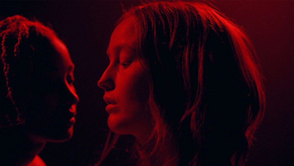 My Animal film still. Two women in red lighting, face to face. Jacqueline Castel film.