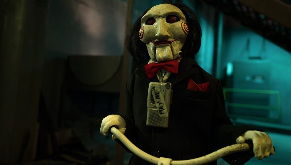 Jigsaw puppet Billy the doll in Saw X. The creepy puppet wears a suit and bow tie.