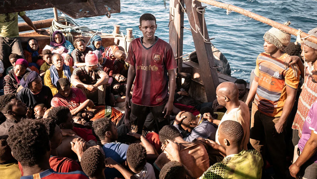 Seydou Sarr in Io Capitano movie scene. Migrants on a boat. Film review.