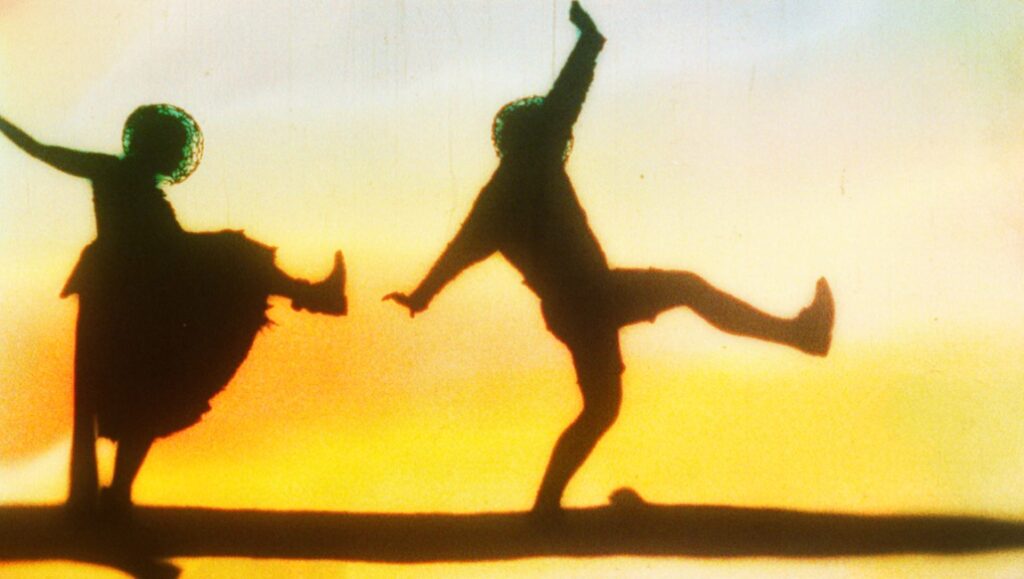 Once Within a Time — Godfrey Reggio Once Within a Time still: Silhouetted figures dance against a yellow-orange sky. Godfrey Reggio film.