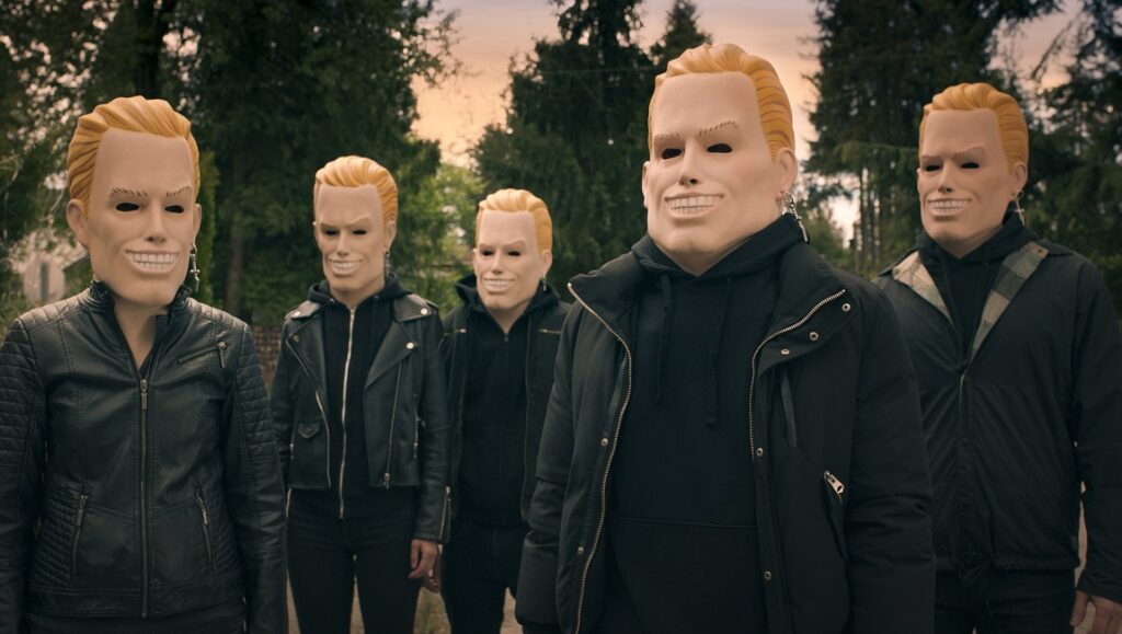 Totally Killer movie still featuring masked killers in blonde masks and dark clothing.