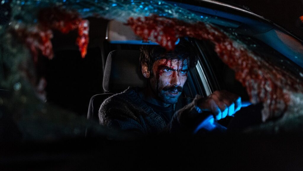 When Evil Lurks — Demián Rugna Still from When Evil Lurks: Man in car with blood spatter on windshield. Horror movie scene.
