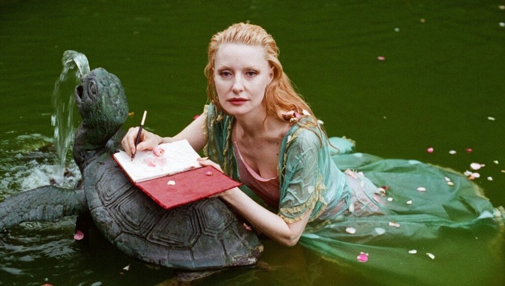The Disappearance of Shere Hite — Nicole Newnham Still from The Disappearance of Shere Hite: Woman in water with turtle fountain, writing in a notebook.