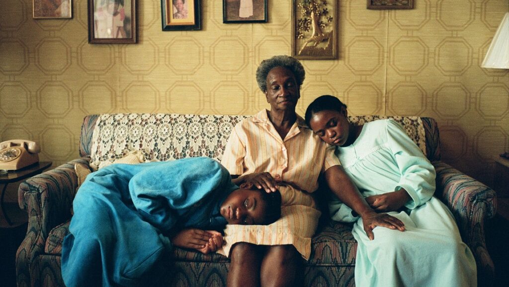 All Dirt Roads Taste of Salt film still. Woman with two girls on couch. Raven Jackson movie.