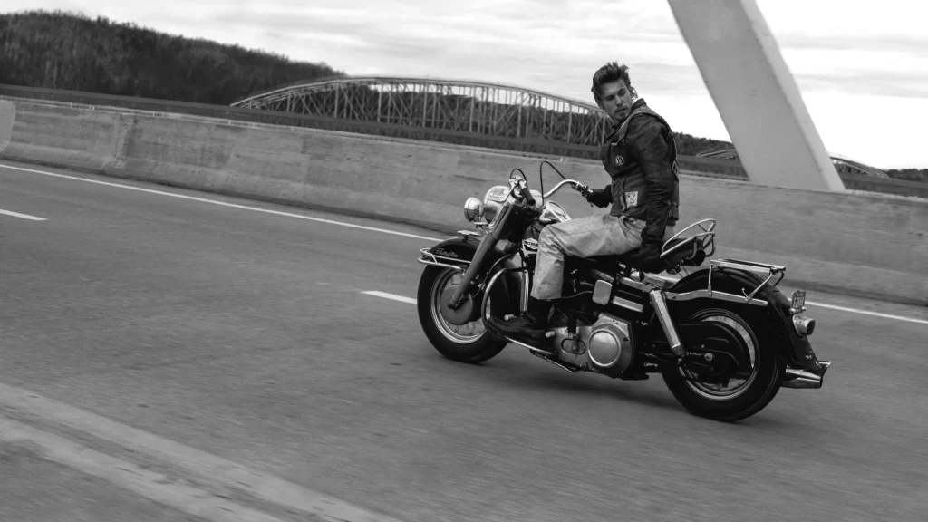 Black and white shot from The Bikeriders movie review. Man on vintage motorcycle.