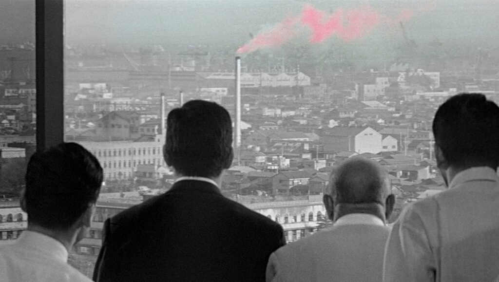 High and Low film still. Men overlook a city with pink smoke. Akira Kurosawa film.