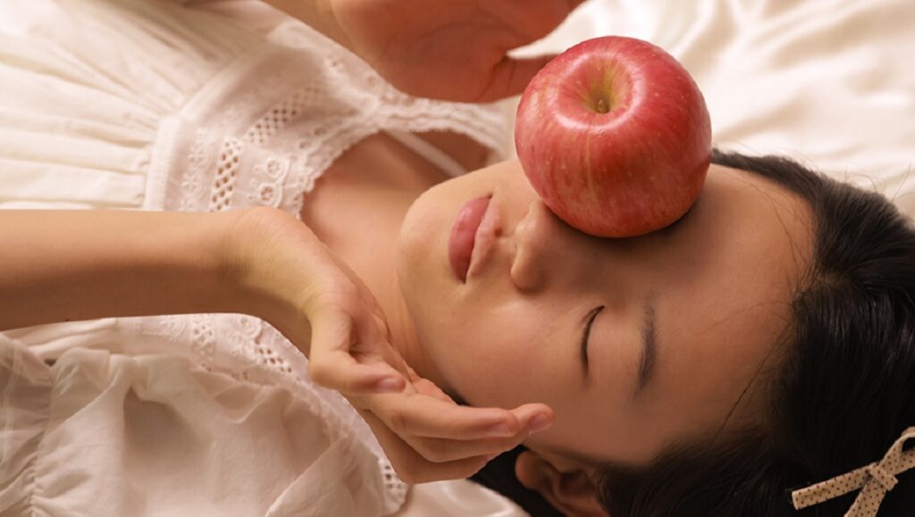Ma Xue's White River: Woman with apple on forehead, eyes closed, wearing white dress.