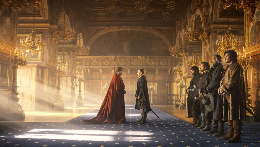The Three Musketeers: Part I – D’Artagnan film scene. Men in period attire in a grand hall.