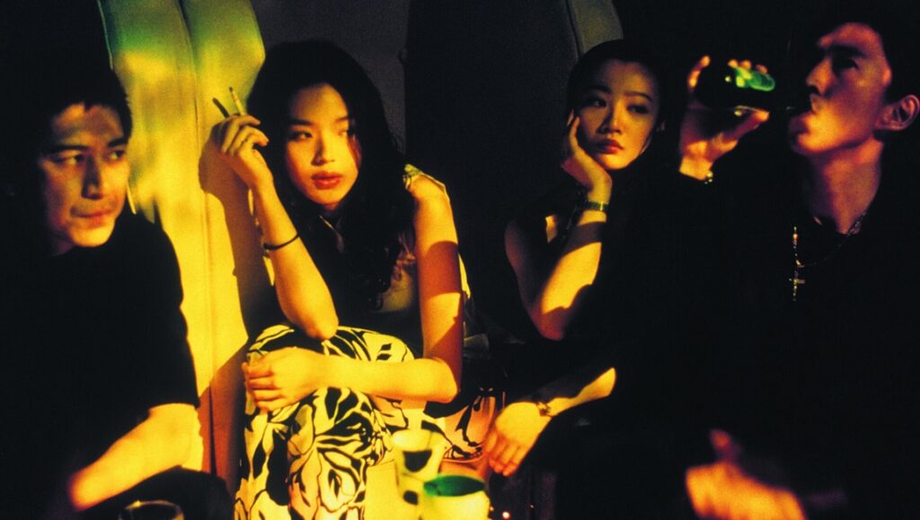 Millennium Mambo film still. Four people sit in a dark, smoky club. A woman smokes a cigarette.