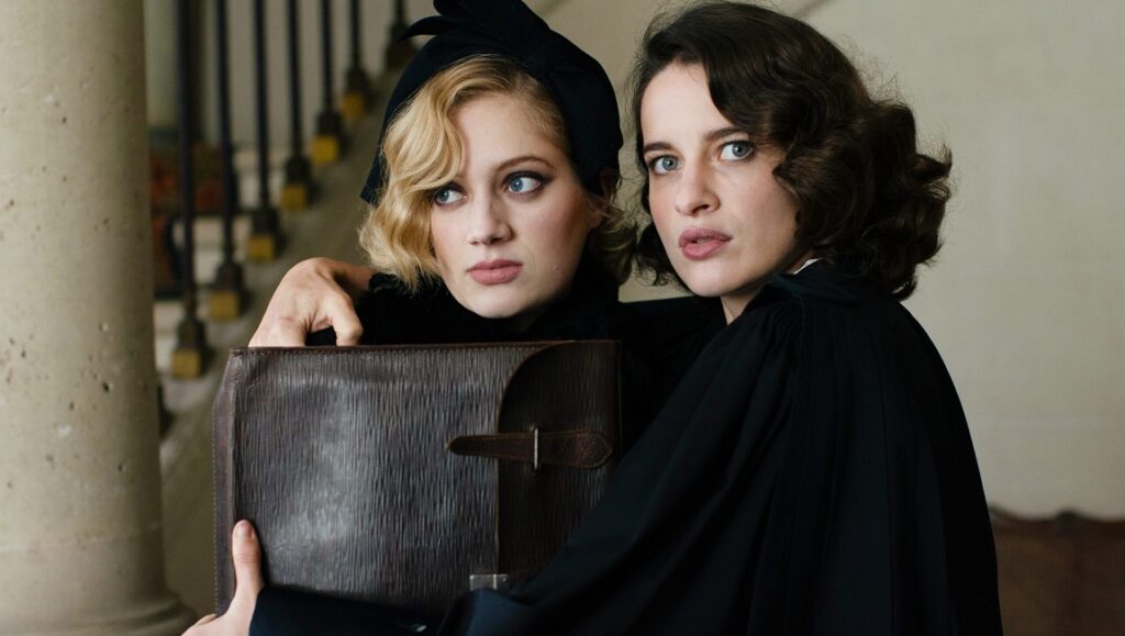 The Crime is Mine film still: Two women, blonde and brunette, holding a large portfolio.
