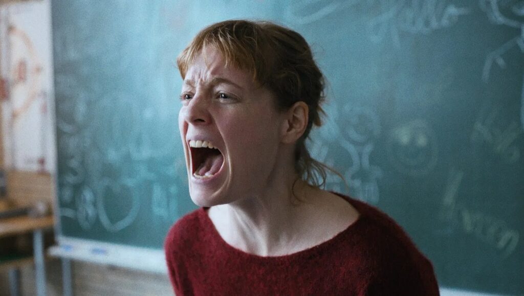 The Teachers' Lounge movie still: Teacher screaming in front of a blackboard. Ilker Çatak film.