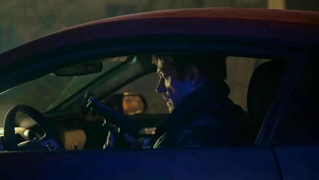 Silent Night — John Woo John Woo's Silent Night: Man driving car at night. Action thriller movie scene.